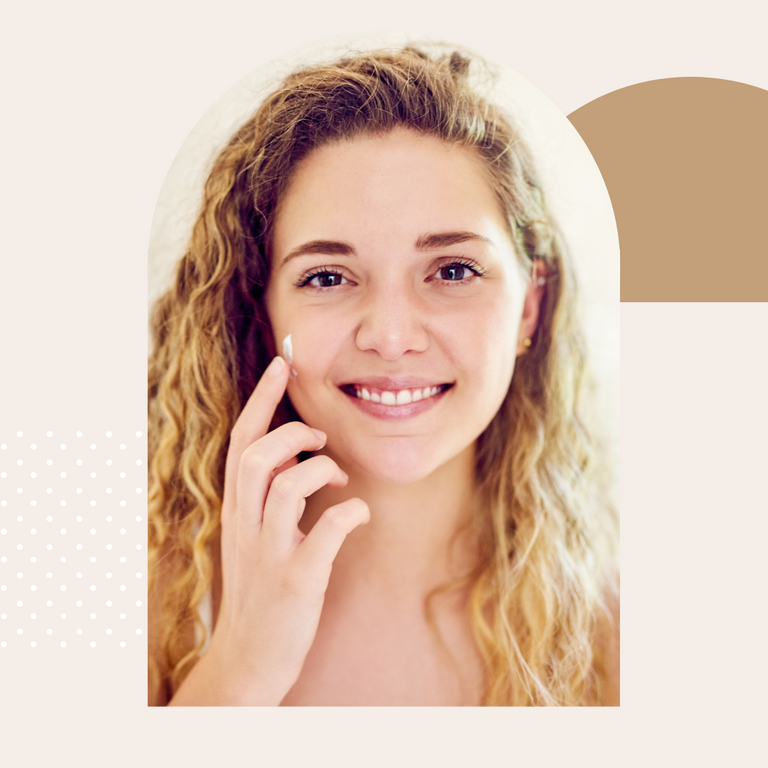 Smiling woman with blonde hair using skincare cream