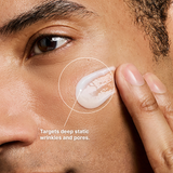 Close-up of a man's face with a dollop of white cream on his cheek, being spread by his finger. Text on the image reads 'Targets deep static wrinkles and pores.