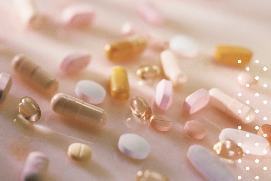 Colorful pills and capsules on a light pink background