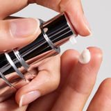 Close-up of a hand applying a small amount of cream to another finger. IS Clinical Daily Dynamic Hydrator