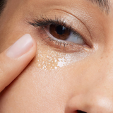 Close-up of a person's eye with a finger touching the skin around the eye area.